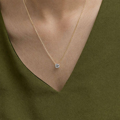Woman wearing a gold chain necklace with a round lab grown diamond pendant from Delux Jewelry.