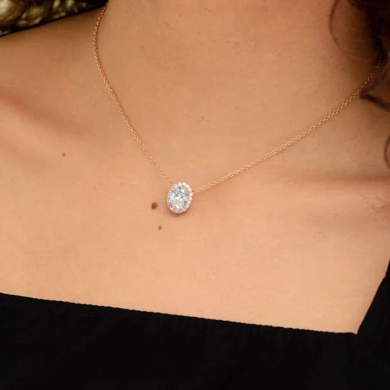 Woman wearing oval halo pendant necklace with lab grown diamonds on a delicate gold chain